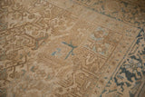 Distressed Heriz carpet's texture, showing cream floral cross-sections and dusty blue border motif.