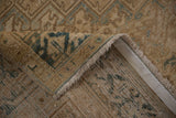 Distressed Heriz carpet corner, showing dusty teal geometric pattern, worn pile, light fringe, and foundation.