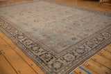 Angled view across the distressed slate blue field and dark brown floral border of a vintage Mahal carpet.