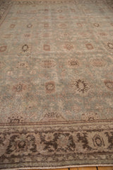Angled perspective of a vintage Mahal carpet highlighting its low pile and sprawling chocolate brown border.