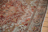 Pinwheel floral border and worn, abrashed field of a vintage Persian Ahar carpet in chestnut rust.