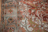 Close view of a vintage Ahar carpet's pinwheel floral border and abrashed, rust-colored field.