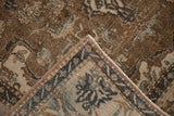 Folded corner of a distressed Isfahan rug with worn brown field, floral motifs in beige and blue, and intact side cord.