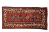 Antique Kazak rug runner with blue stepped center medallions on a brick red field and geometric borders.
