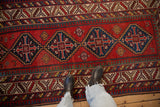 Antique Kazak runner's stepped medallions in sapphire blue against a brick red field and pawn motif borders.