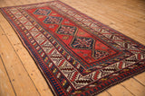 Angled view of an antique Kazak runner highlighting its column of stepped geometric medallions.