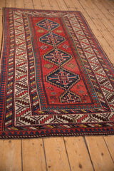 Angled perspective of an antique Kazak runner's blue stepped medallions on a brick red field.