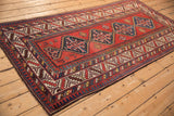 Angled view of an antique Kazak runner highlighting its central medallions and complex geometric borders.