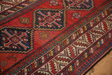 Angled view detailing the stepped medallions and geometric pawn motif border of an antique Kazak rug.