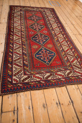 Angled perspective of an antique Kazak runner, showcasing its column of geometric medallions and intricate borders.