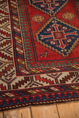 Detailed view of the reciprocating pawn motif and serrated leaf border on an antique Kazak rug.