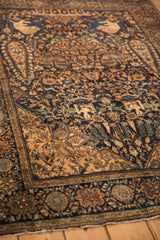 Angled view of the antique pictorial rug's detailed hunting scene and botehs in navy blue and sandalwood.