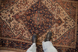 Distressed low pile and intricate navy blue medallion of a vintage Persian Malayer rug.