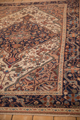 Scrolled arabesques and floral details on a vintage distressed Malayer rug's short-pile texture.