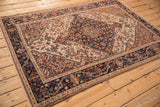 Angled view of the distressed vintage Malayer rug, highlighting its rich navy and copper palette.