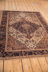 Low angle view of a vintage Malayer rug, showing the navy blue medallion and intricate floral patterns.
