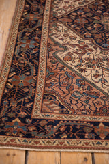Intricate floral vines in copper and mallard green on the navy blue border of a vintage Malayer rug.