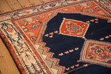 Corner detail of a vintage Malayer rug with terracotta spandrels and a Serbend-style ivory border.