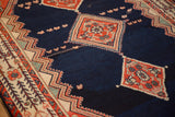 Detail showing the low pile texture of a vintage Malayer carpet's navy blue field and floral medallions.