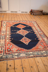 Full view of a vintage Malayer carpet highlighting its geometric triple medallion and Serbend-style border.