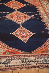 Angled view of terracotta medallions on the low-pile navy field of a vintage Malayer rug.