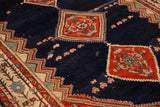 Texture of a vintage Malayer carpet's navy field, showing red medallions and areas of wear down to the knot heads.