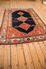Angled view of a vintage Malayer carpet's navy field and red triple center medallions.