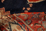 Folded vintage Malayer rug showing the rich texture of its navy field and intricate red and ivory border.