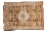 Vintage distressed Kars carpet with a triple stepped medallion on an abrashed field of sand and coffee brown.