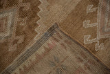 View of the hand-knotted weave and secured selvage on a distressed Kars carpet corner.