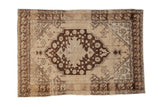 Cream and dark brown vintage distressed Oushak rug with shield medallion and tulip border.