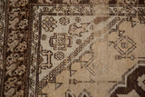 Distressed vintage Oushak rug corner, showing cream and chocolate geometric spandrel and tulip border.