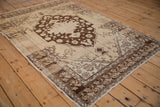 Distressed cream corner spandrel and dark chocolate brown tulip border of an Oushak rug.