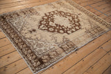 Vintage distressed Oushak rug: cream field, chocolate brown medallion, floral border, heavy abrashes.
