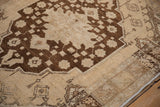 Close-up of a distressed vintage Oushak rug, showing worn brown medallion floral motifs on a cream field.