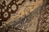 Folded vintage Distressed Oushak rug showing worn brown and cream pile with heavy abrash.