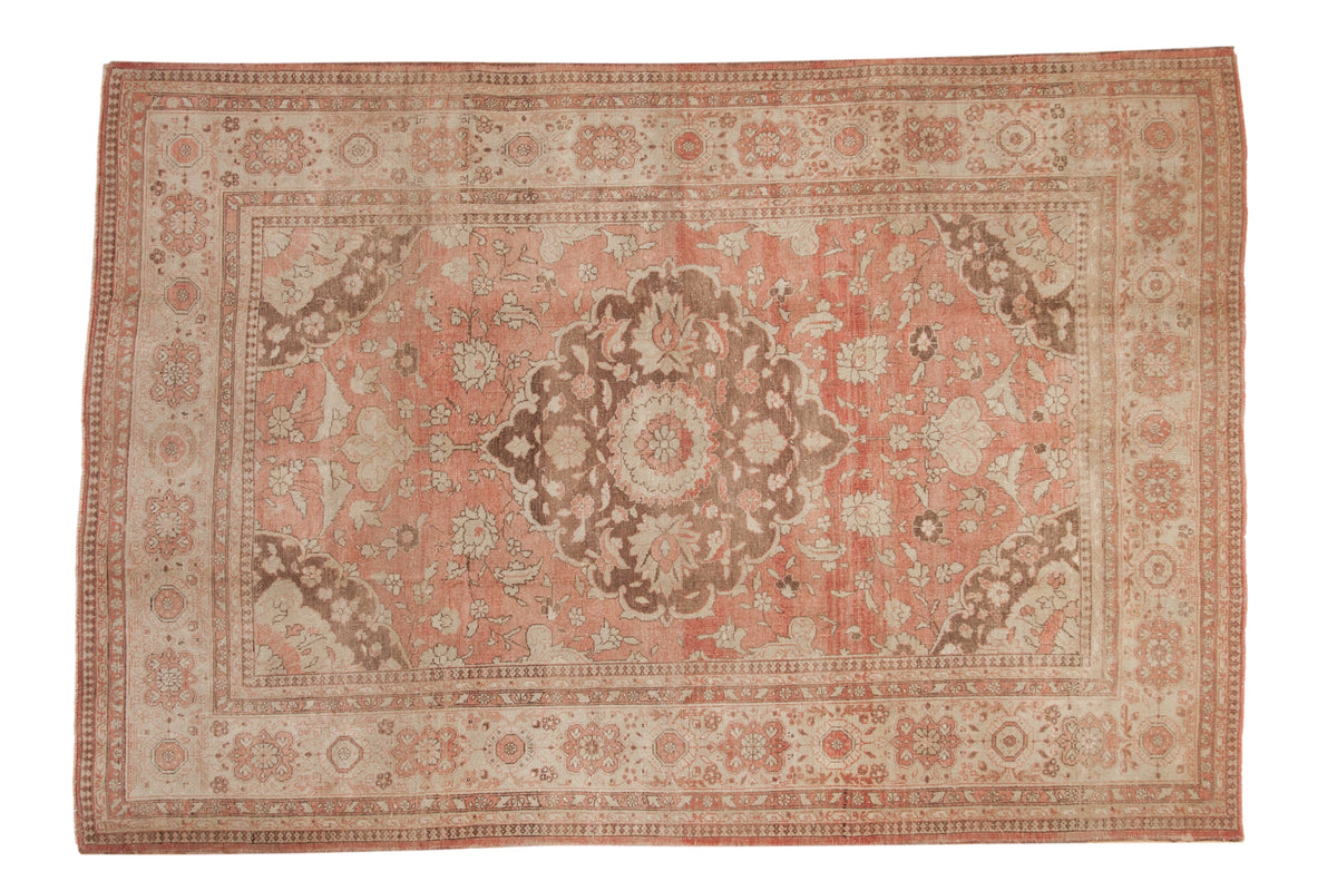 Distressed vintage Oushak carpet with a central floral medallion in dusty rose, brown, and ivory tones.