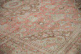 Low-pile texture of a distressed Oushak carpet with floral and pawn motifs in dusty rose and brown.