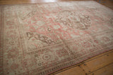 Full angled view of a vintage distressed Oushak carpet, showcasing its dusty rose and coffee brown floral design.