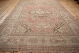 Low angle on a distressed Oushak rug, showing the worn texture of its decorative pomegranate border.