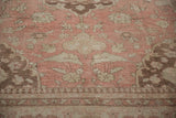 Low-angle view of the pawn design border and worn pile on a dusty rose Oushak carpet.