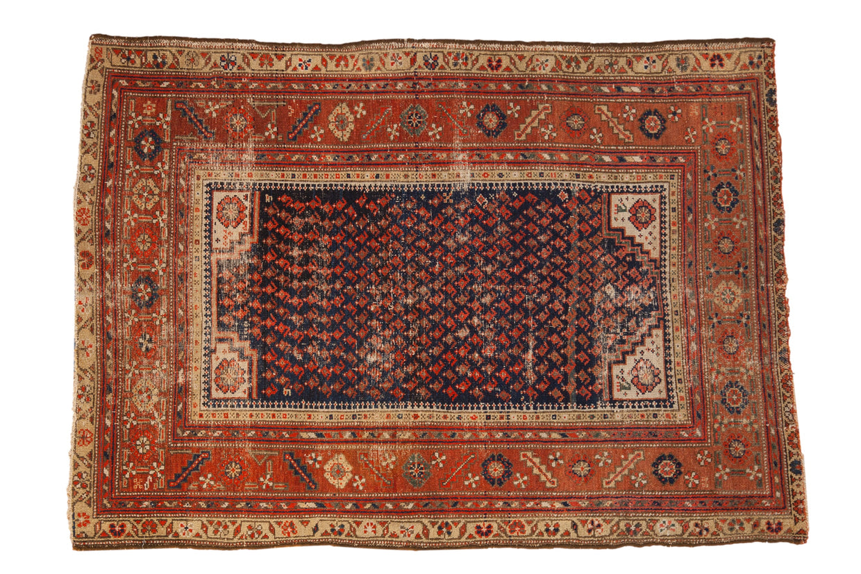 Antique Malayer rug with a navy blue allover boteh pattern, brick red borders, and visible wear.