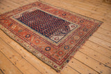Corner of antique Malayer rug, with brick red borders and navy field's worn boteh pattern.