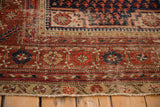 Worn pile and tattered end of the antique Malayer rug, showing brick red and beige patterns.