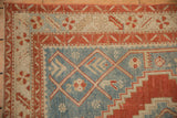 Corner detail of a vintage Karabagh rug, with geometric borders in red and ivory framing a dusty sky blue field.