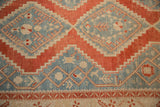 Close-up of stylized serpent and germinating plant motifs on the distressed hand-knotted pile.