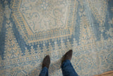 Distressed low-pile texture of a vintage Persian Veece carpet in soft blue and ivory.