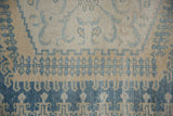 Detail of the worn, hand-knotted pile and border motifs in dusty blue and ivory on a vintage Veece carpet.
