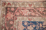 Patinaed floral palmettes and cobalt blue accent on a vintage distressed Oushak rug pile.