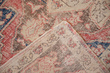 Hand-knotted foundation reveals the distressed ivory, red, and beige pile of the Oushak rug.